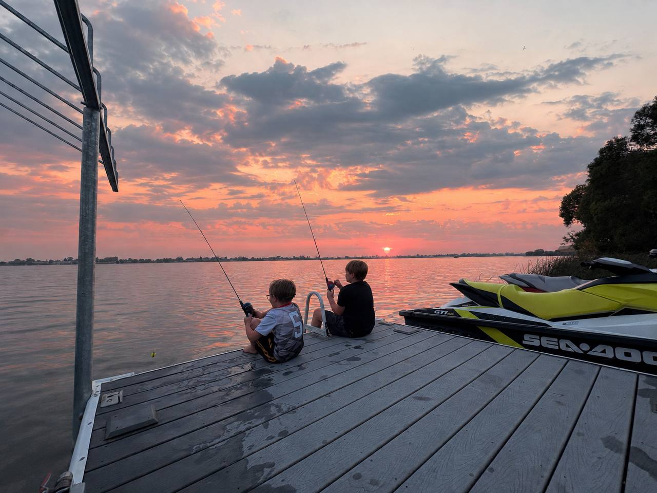 Sunset from the dock — kids on the end of the dock with rods out, jet ski on the lift